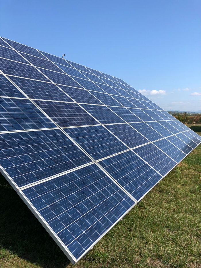 Solar panels in a green field on a sunny day, showcasing renewable energy in Tortona, Italy.
